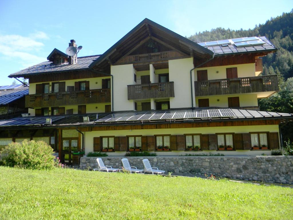 a large building with two chairs in front of it at Albergo Nuoitas in Forni di Sopra