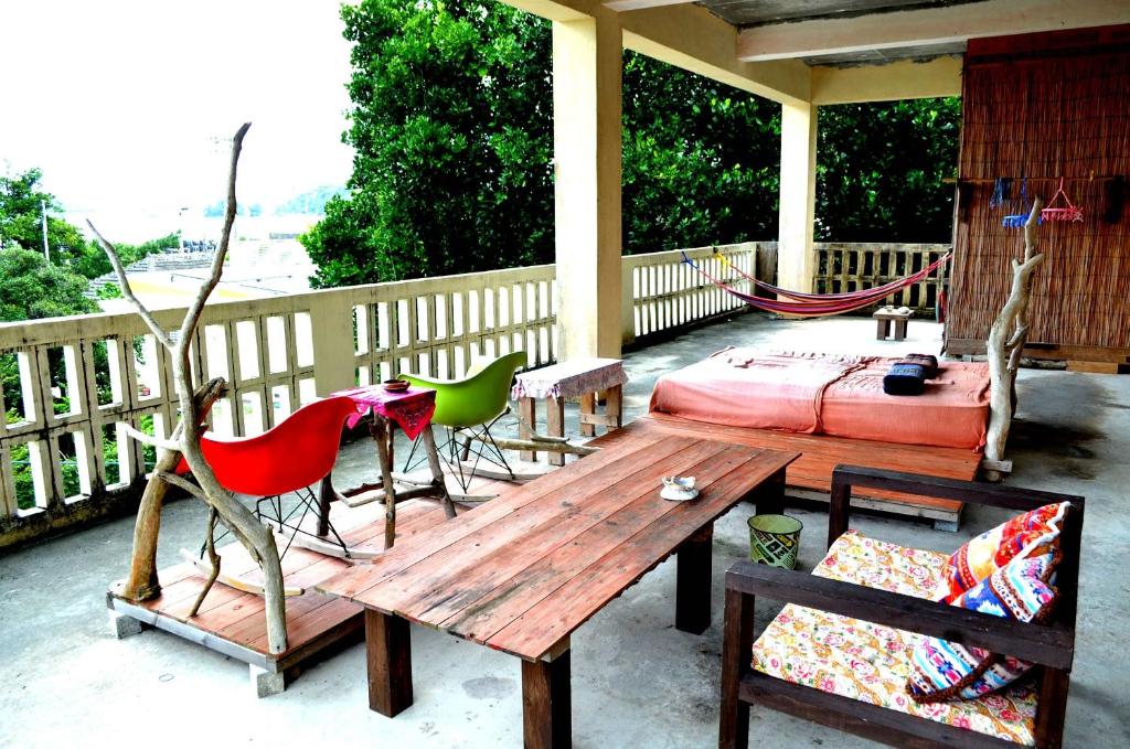 een houten tafel en stoelen op een veranda met een bed bij Asian guesthouse Border in Nago