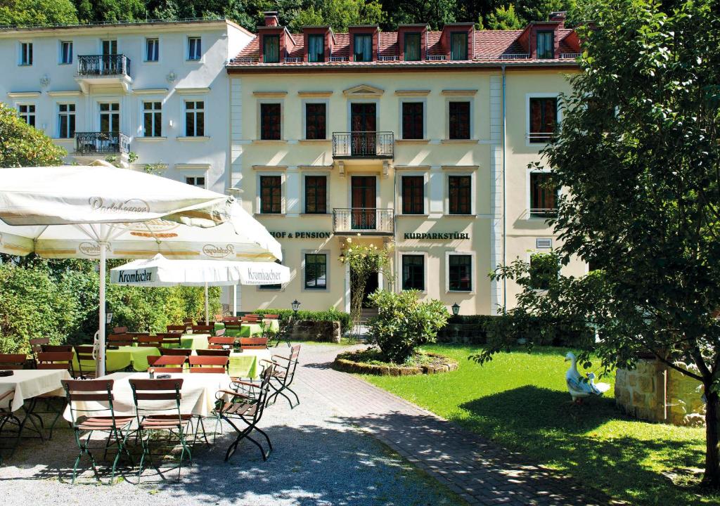 a hotel with tables and chairs and an umbrella at Kurparkstübl Bad Schandau in Bad Schandau