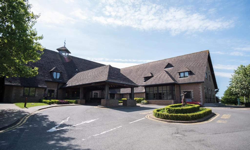 un grand bâtiment avec une tour d'horloge dans une rue dans l'établissement Kettering Park Hotel and Spa, à Kettering