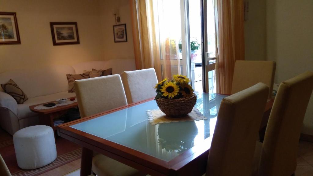 einen Esstisch mit einer Vase mit Sonnenblume darauf in der Unterkunft Apartment Tatjana in Vis