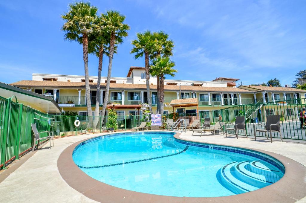 a swimming pool with palm trees and a building at Bay Front Inn in Santa Cruz