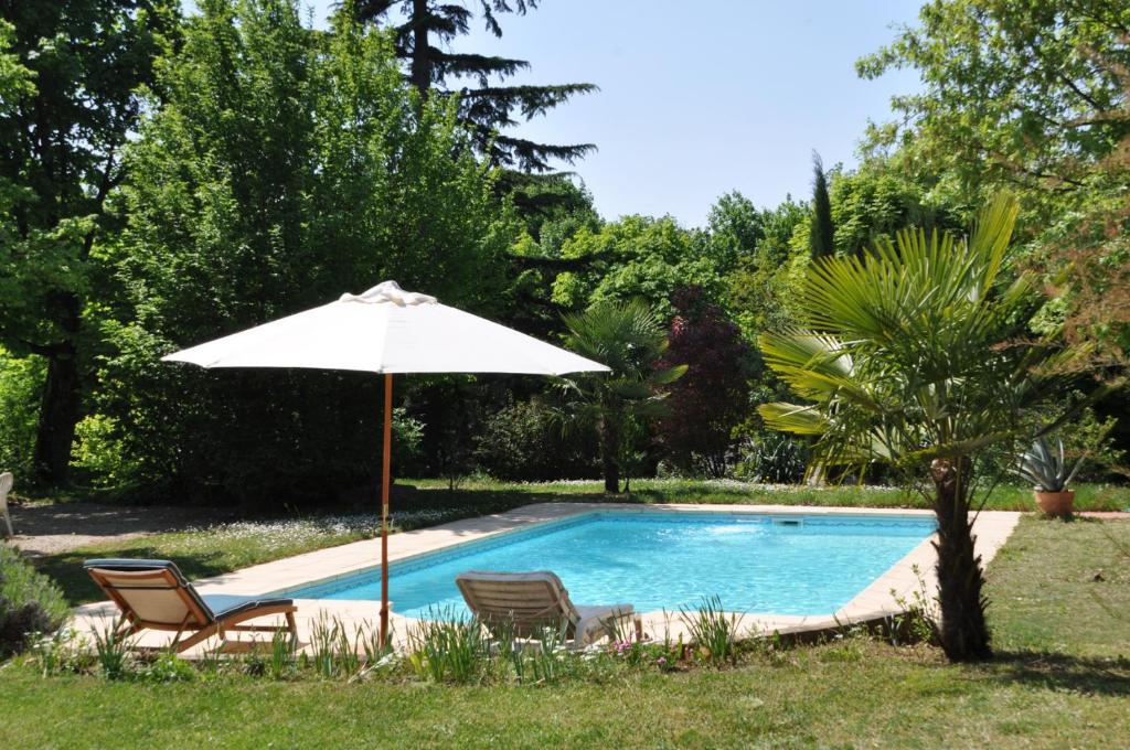 a pool with two chairs and an umbrella at Villa Castel Maison Meublée in Rillieux