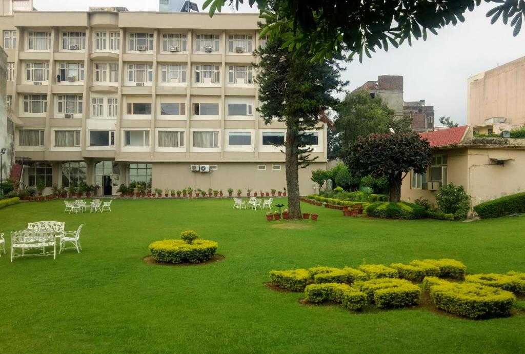a large building with a green yard with tables and chairs at Cardinal Ambica in Katra