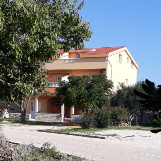a large house with trees in front of it at Apartmani Ruža in Novalja