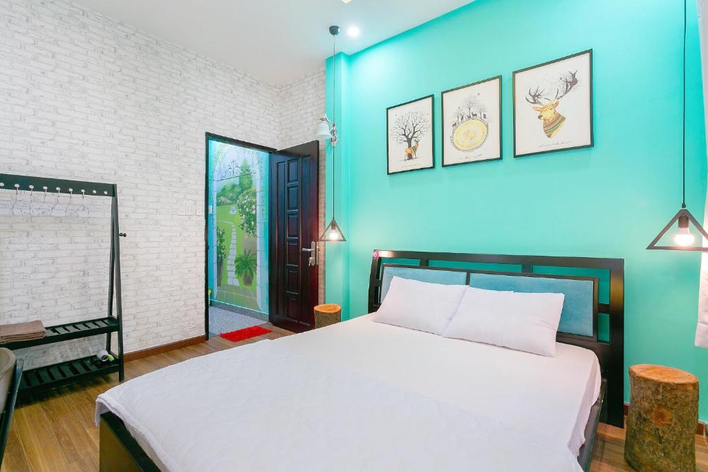 - une chambre avec un lit blanc et un mur bleu dans l'établissement Qcub3 Homestay, à Hô-Chi-Minh-Ville
