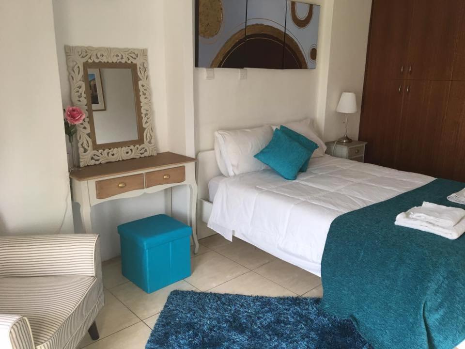 a bedroom with a bed and a mirror and a stool at Marina Apartments 211 in Larnaka