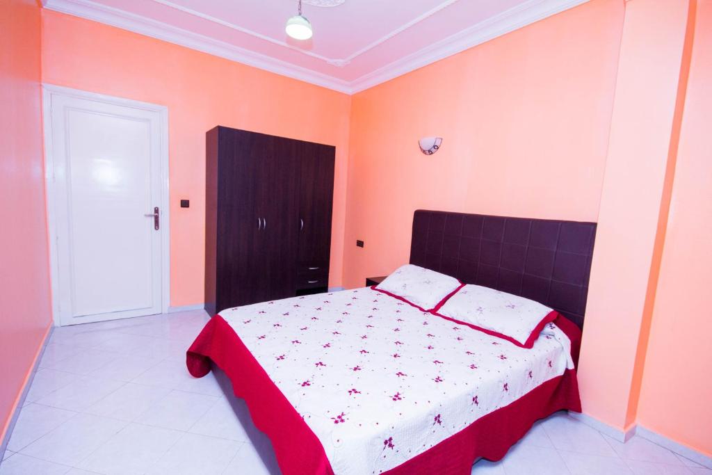Schlafzimmer mit einem Bett mit roten und orangefarbenen Wänden in der Unterkunft Appart Hotel Wassila in Nador