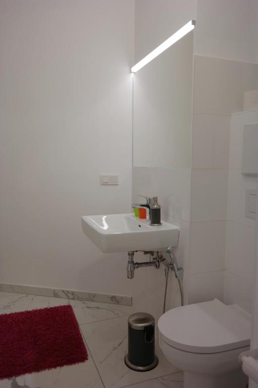 a white bathroom with a sink and a toilet at Pension am Wienfluss in Vienna