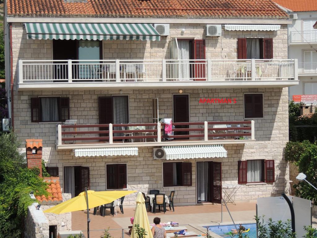 um edifício com um pátio e uma varanda com uma mesa em Apartments Bezmalinović 2 em Bol