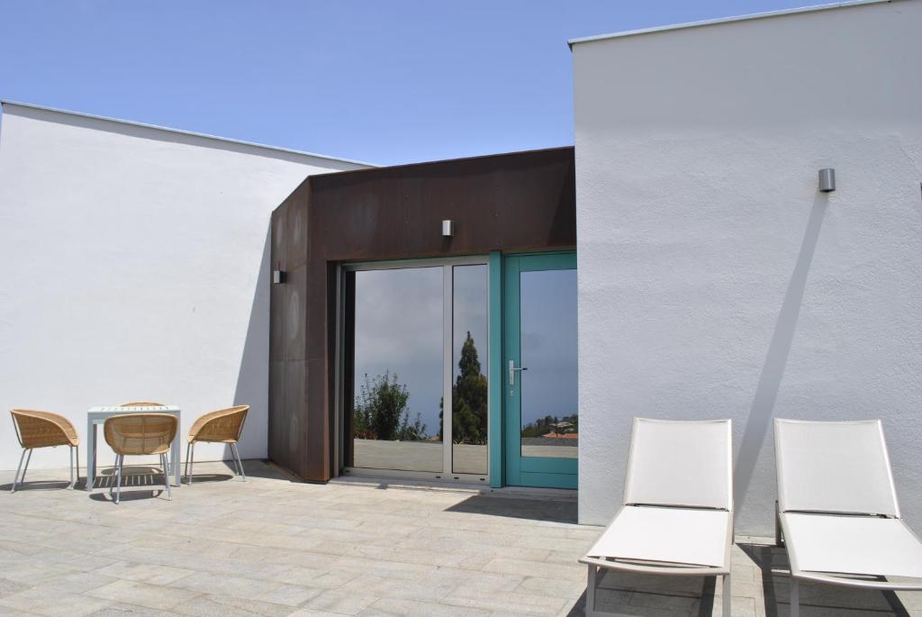 un patio con sillas, una mesa y puertas de cristal en VILLA HORIZONTE, en Puntagorda