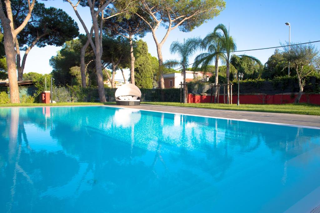 una piscina azul con árboles en el fondo en Relais Villa Italia en Selcetta