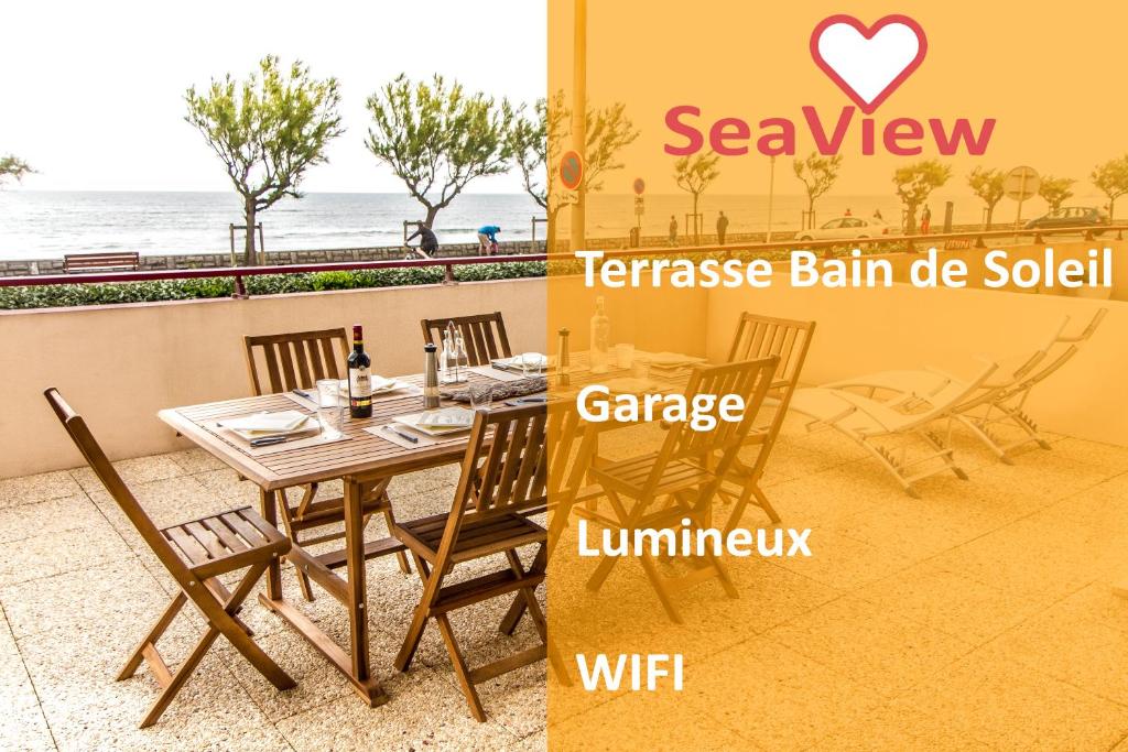 a wooden table and chairs in a room with the ocean at Front de Mer in Hendaye