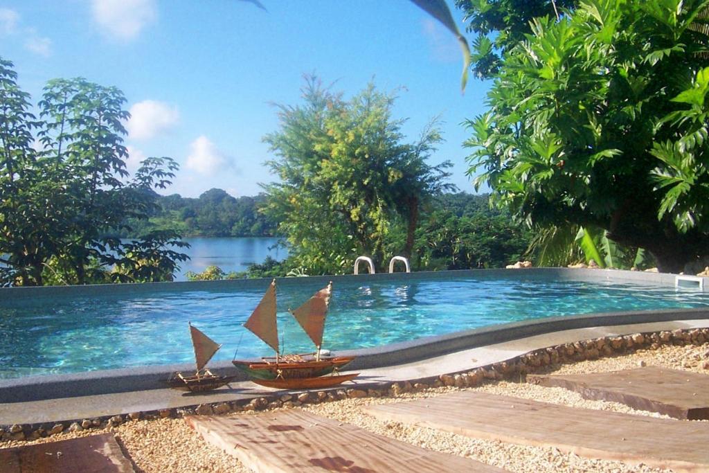 uma piscina com duas cadeiras e um barco em Seachange Lodge em Port Vila