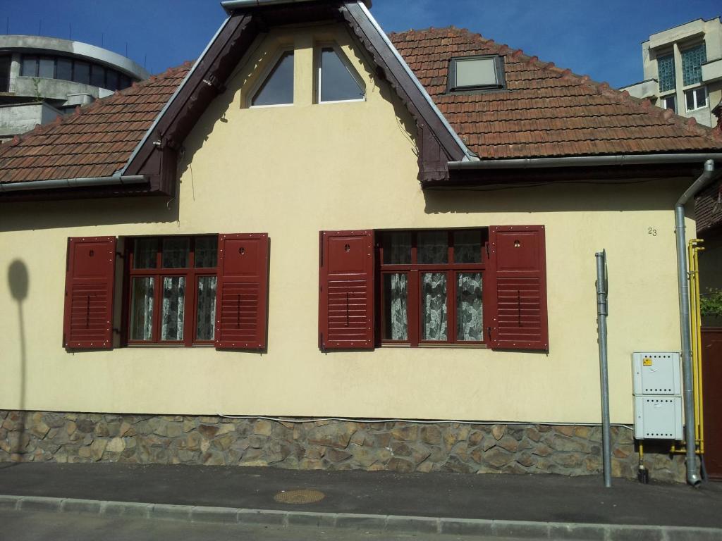 a house with red shuttered windows on a street at Apartament Roza in Braşov