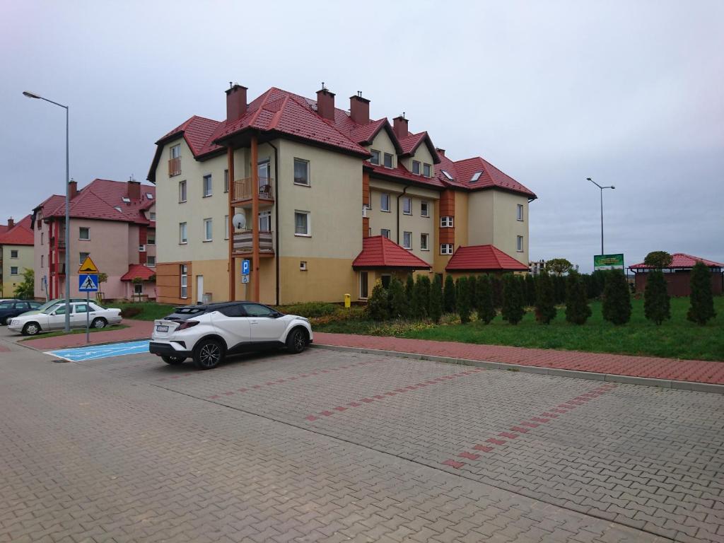 a white car parked in front of a large building at Apartament Boróweczka in Polkowice
