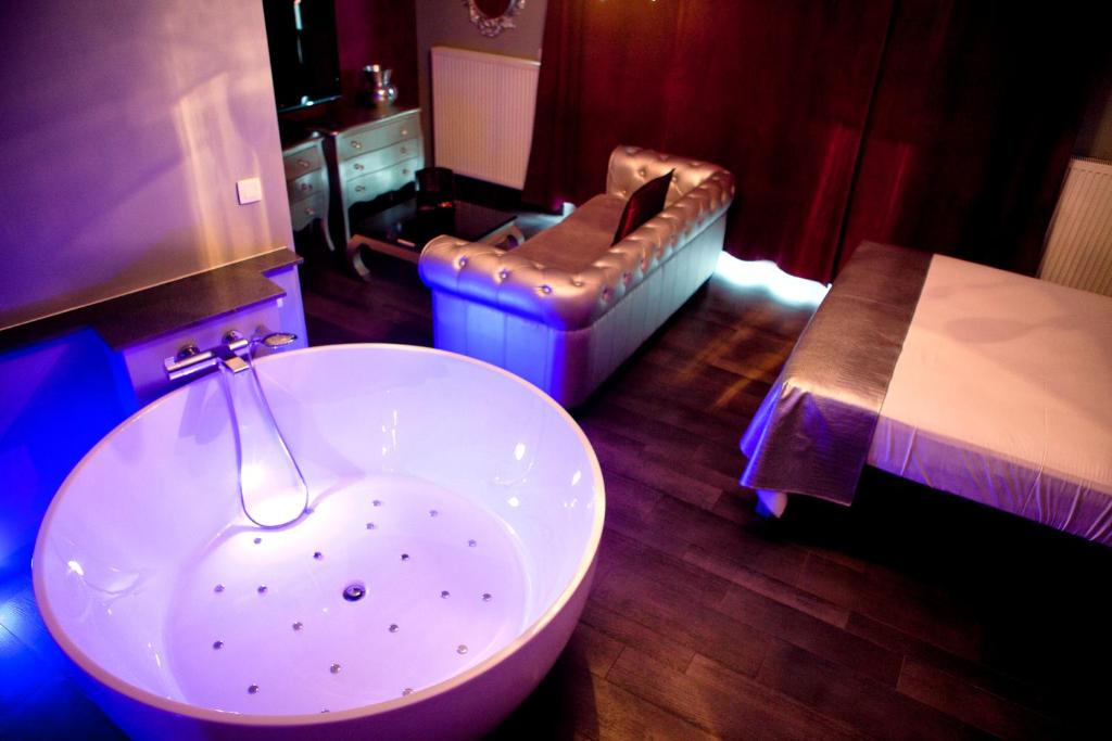 a bathroom with a white bath tub and a chair at Hôtel Verone - Liège Centre in Liège