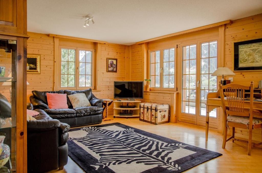 uma sala de estar com um sofá e uma televisão em Apartment Saphir - GRIWA RENT AG em Grindelwald