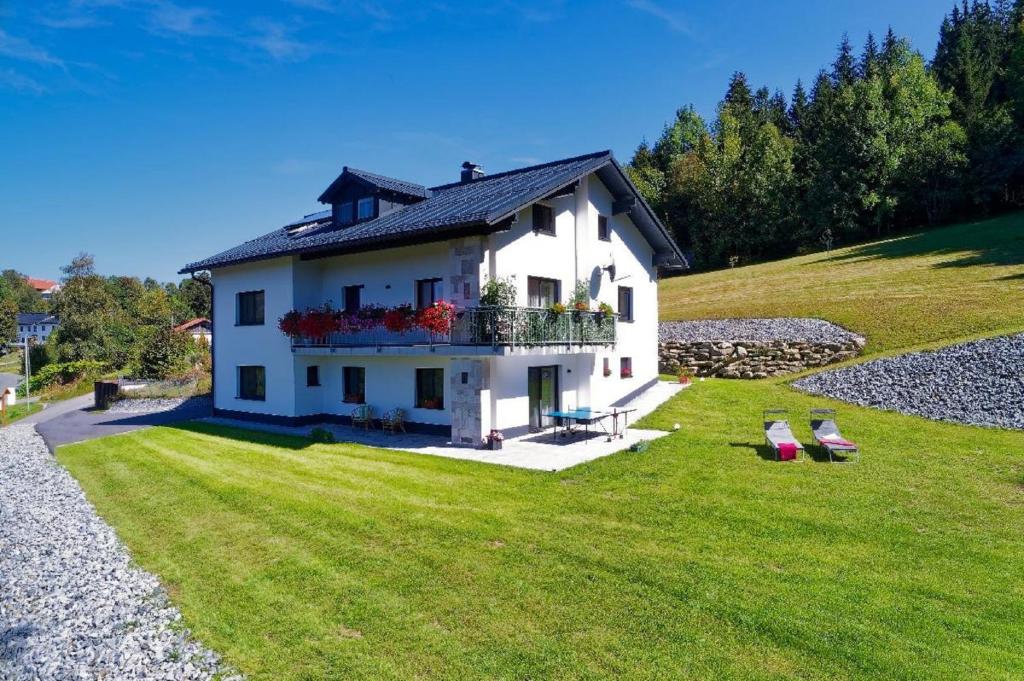 ein weißes Haus mit einem Balkon auf einem Grasfeld in der Unterkunft Panoramablick in Mauth