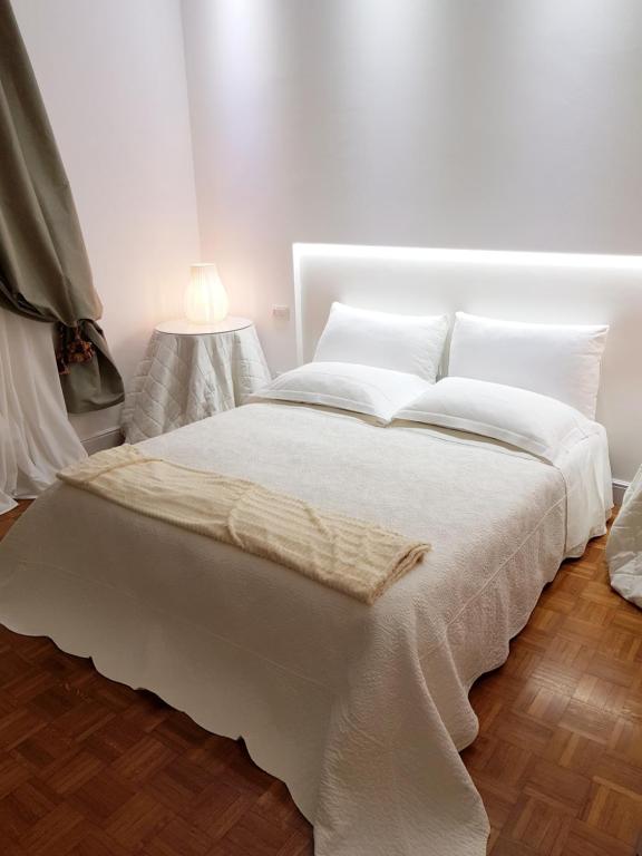 ein weißes Bett mit weißer Bettwäsche und Kissen in der Unterkunft CharmeRooms Palazzo Stampa in Bergamo