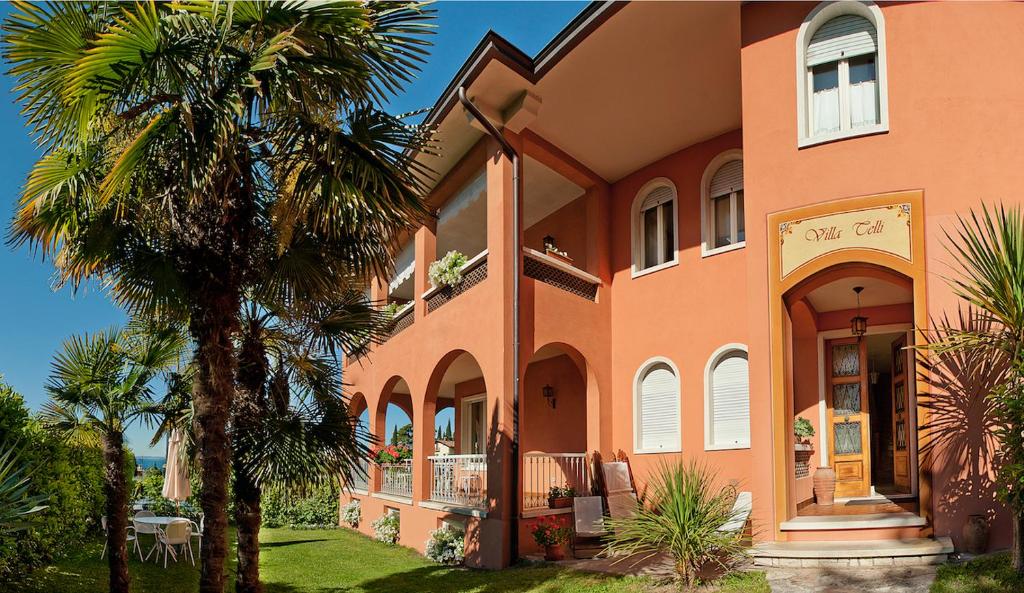 a large orange house with a palm tree in front of it at Villa Telli in Garda