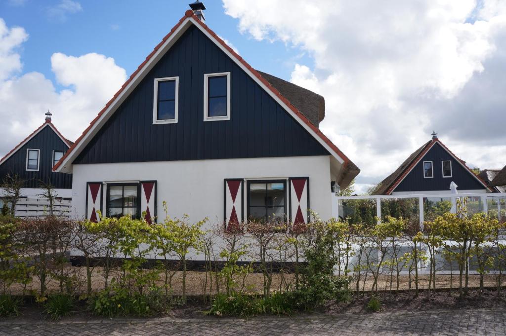 a house with a black roof and red trim at Villa Buiten 130 met Sauna in Callantsoog