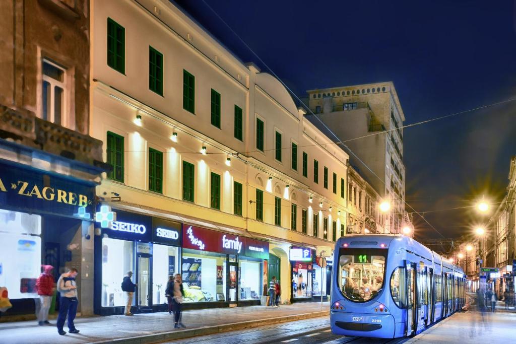 a blue train on a city street at night at Hotel PARK 45 in Zagreb