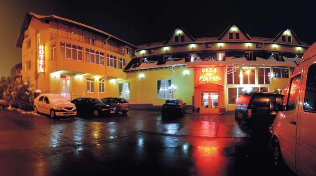 Scheia的住宿－Hotel Casa de Piatra，一座有照明的建筑,里面的汽车停在停车场
