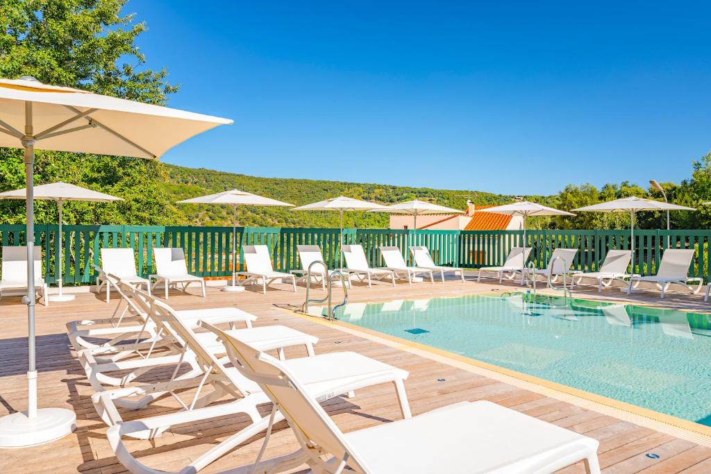 a pool with chairs and umbrellas on a deck at La Pinède in Amélie-les-Bains-Palalda