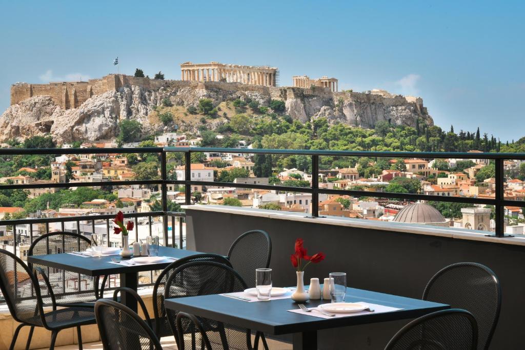 2 mesas en un balcón con vistas a la acrópolis en Astor Hotel, en Atenas