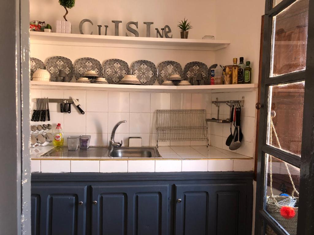 a kitchen with a sink and shelves with dishes at Dar Christine in Marrakesh