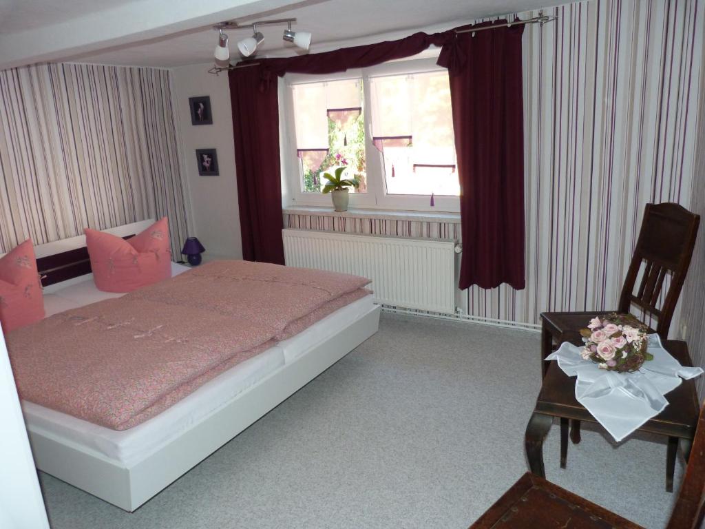 een slaapkamer met een bed, een raam en een stoel bij Ferienhaus Scheper in Bad Frankenhausen