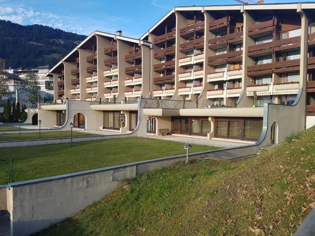 un grand bâtiment avec un champ herbeux devant lui dans l'établissement Résidence Panorama A201, à Villars-sur-Ollon