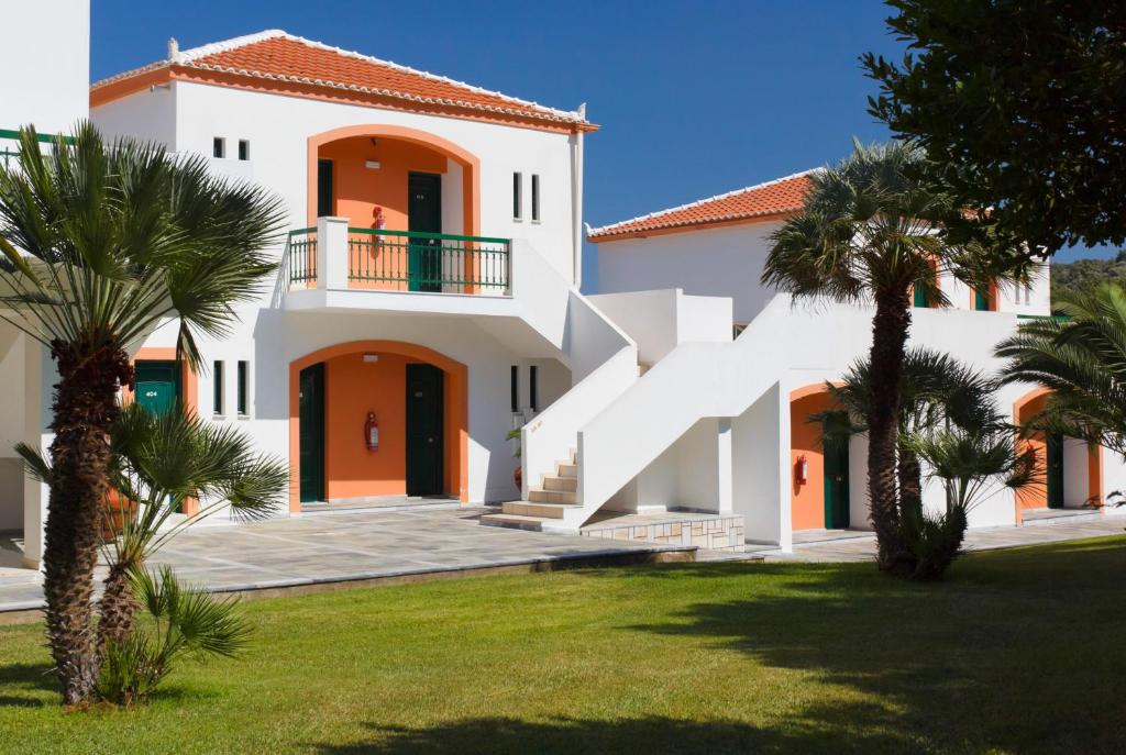 a white house with orange doors and palm trees at Arion Hotel in Kokkari