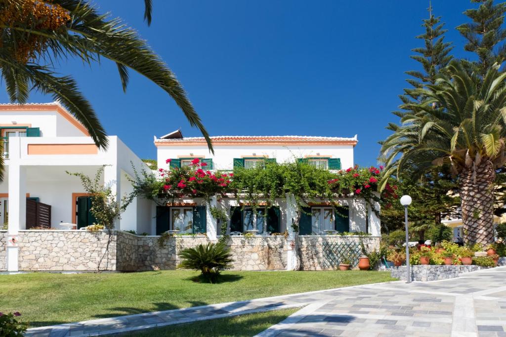 a white house with flowers on a stone wall at Arion Hotel in Kokkari
