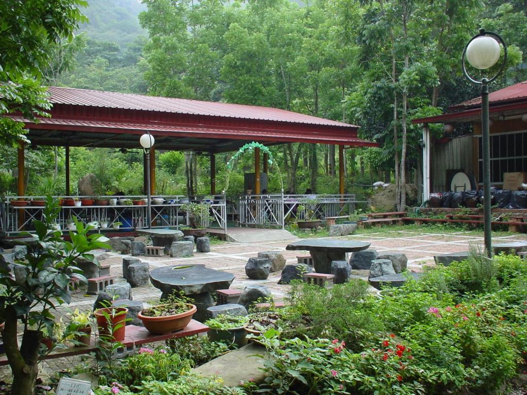 um pavilhão com mesas e bancos num jardim em De Wang Villa em Meinong