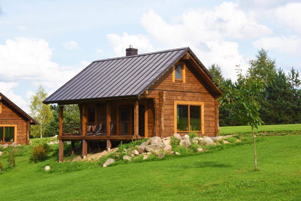 una cabaña de madera con techo negro en un césped verde en Vip Forest dreams villa, en Anykščiai