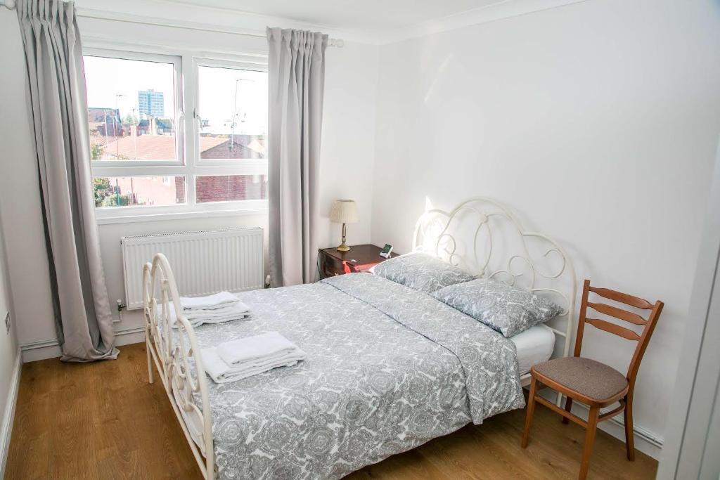 Double bedroom in ashared flat في سوتون: غرفة نوم بسرير وكرسي ونافذة