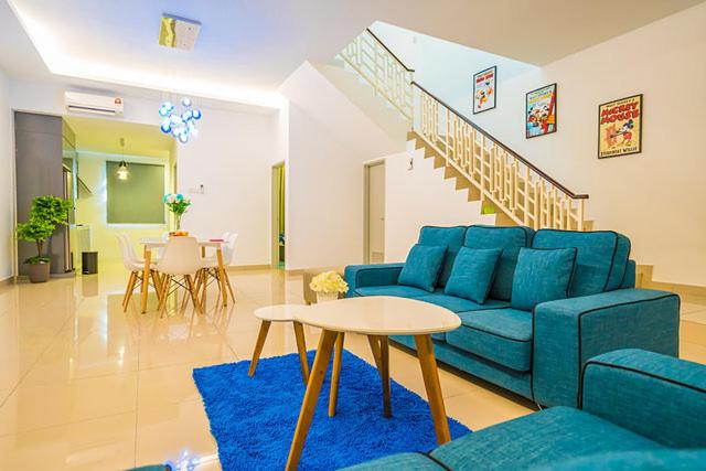 een woonkamer met een blauwe bank en een tafel bij 4-Bedrm ensuite family friendly house near Aeon Bukit Indah in Johor Bahru