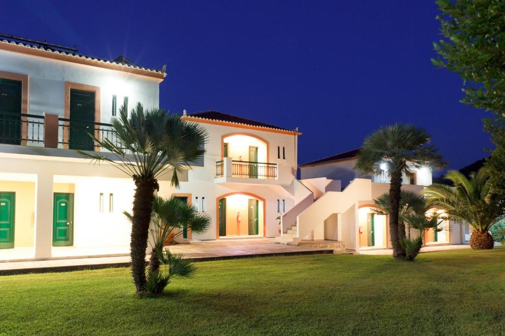 a large white house with palm trees in the yard at Arion Hotel in Kokkari