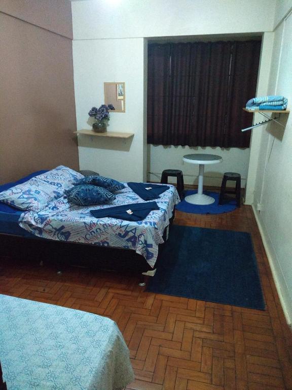 Habitación con 2 camas, mesa y ventana en Hotel Santa Sara, en Ribeirão Preto