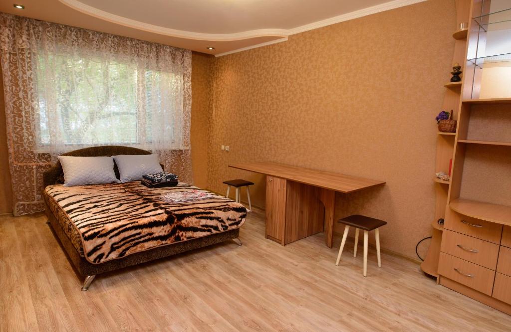 a bedroom with a bed and a desk and a window at Апартаменты Deluxe in Cherkasy