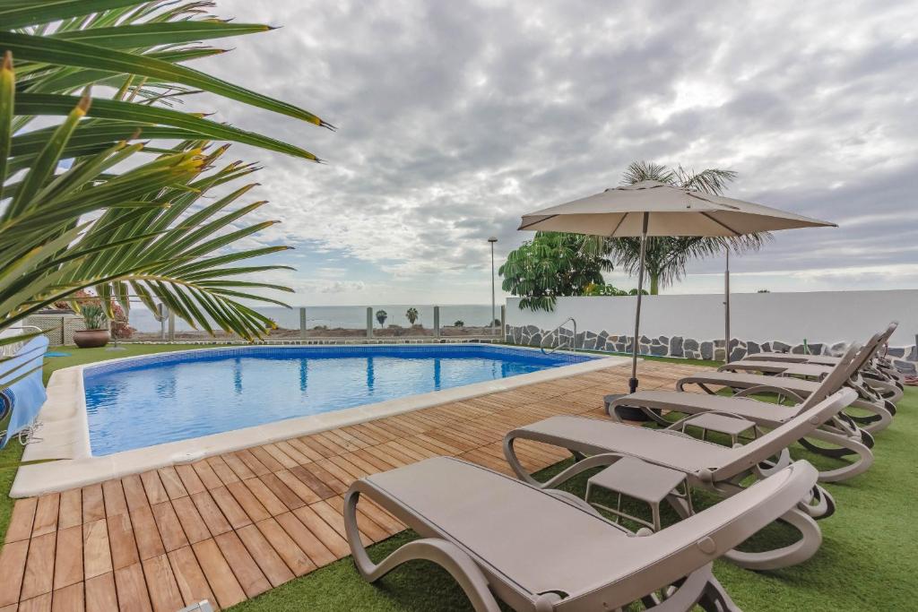 a swimming pool with lounge chairs and an umbrella at Villa Isabella, Luxury Villa with Heated Pool Ocean View in Adeje, Tenerife in Adeje