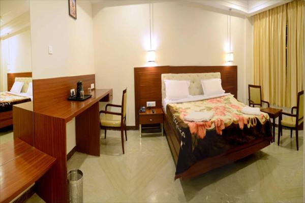 a hotel room with a bed and a desk at Raya's Grand in Kumbakonam