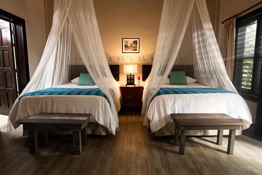 a bedroom with two beds with mosquito nets at Hotel Jungle Lodge Tikal in Tikal