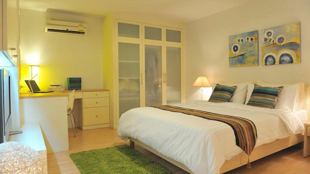 a bedroom with a bed and a desk with a laptop at Duplex 21 Apartment in Bangkok