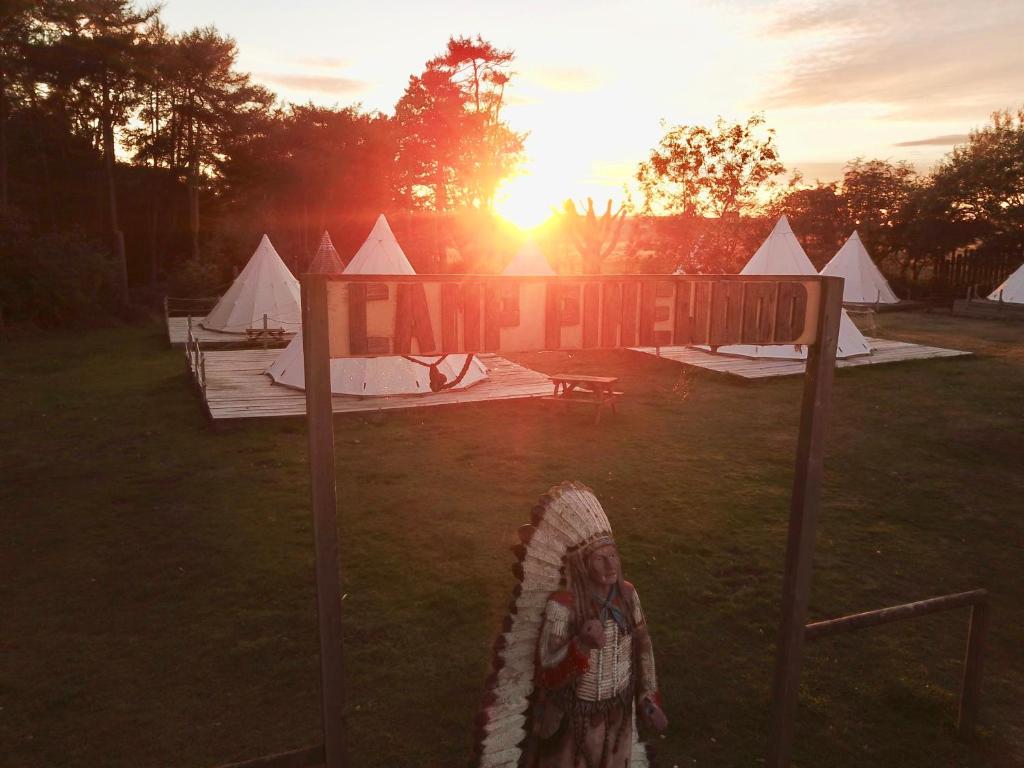 un grupo de tiendas de campaña en un campo con la puesta de sol en Pinewood Park - Tipis, Hot Tubs and Lodges en Scarborough