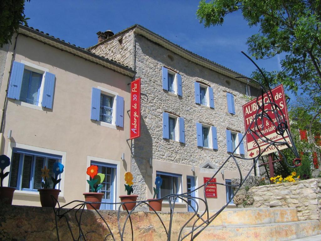 un bâtiment avec des panneaux rouges devant lui dans l'établissement Auberge de Trente Pas, à Saint-Ferréol-Trente-Pas