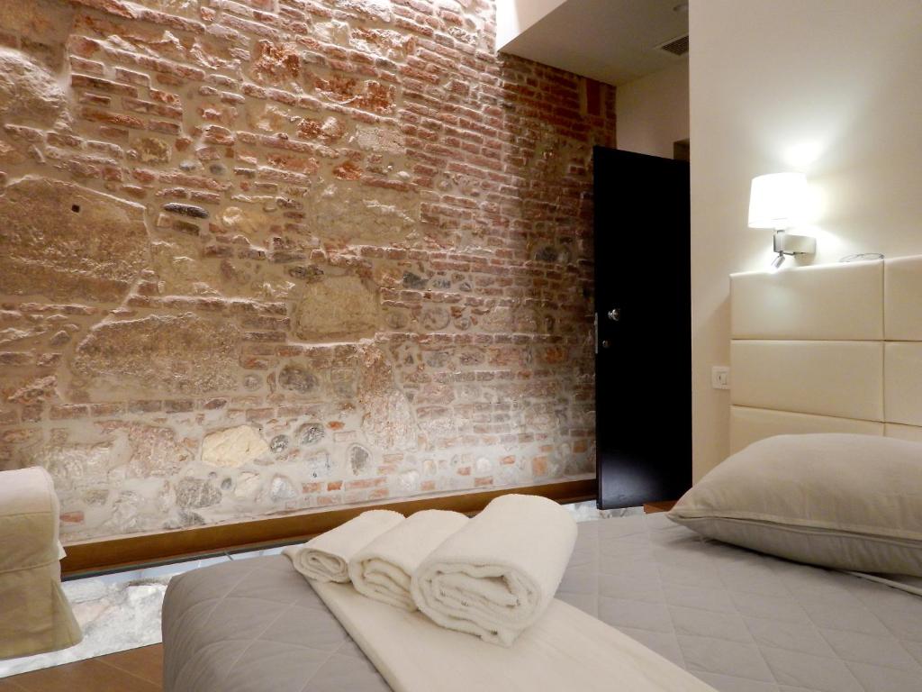 1 dormitorio con pared de ladrillo y 1 cama con toallas en Arena Luxury Suite en Verona