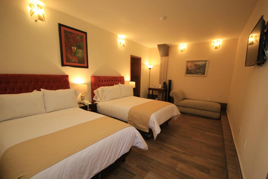 a hotel room with two beds and a chair at Hotel Boutique Ponciano in Guanajuato